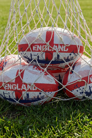 White and red Optimum England rugby balls with St George's cross and ENGLAND print in a net bag on grass - Optimum