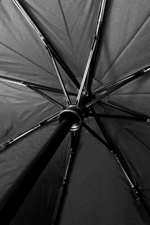 Underside of open black Optimum umbrella showing ribs, frame and central shaft, close-up - Optimum