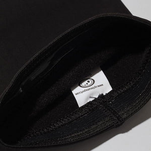 Close-up of black Optimum Hawkley arm warmer with white sewn-in branded care label - Optimum