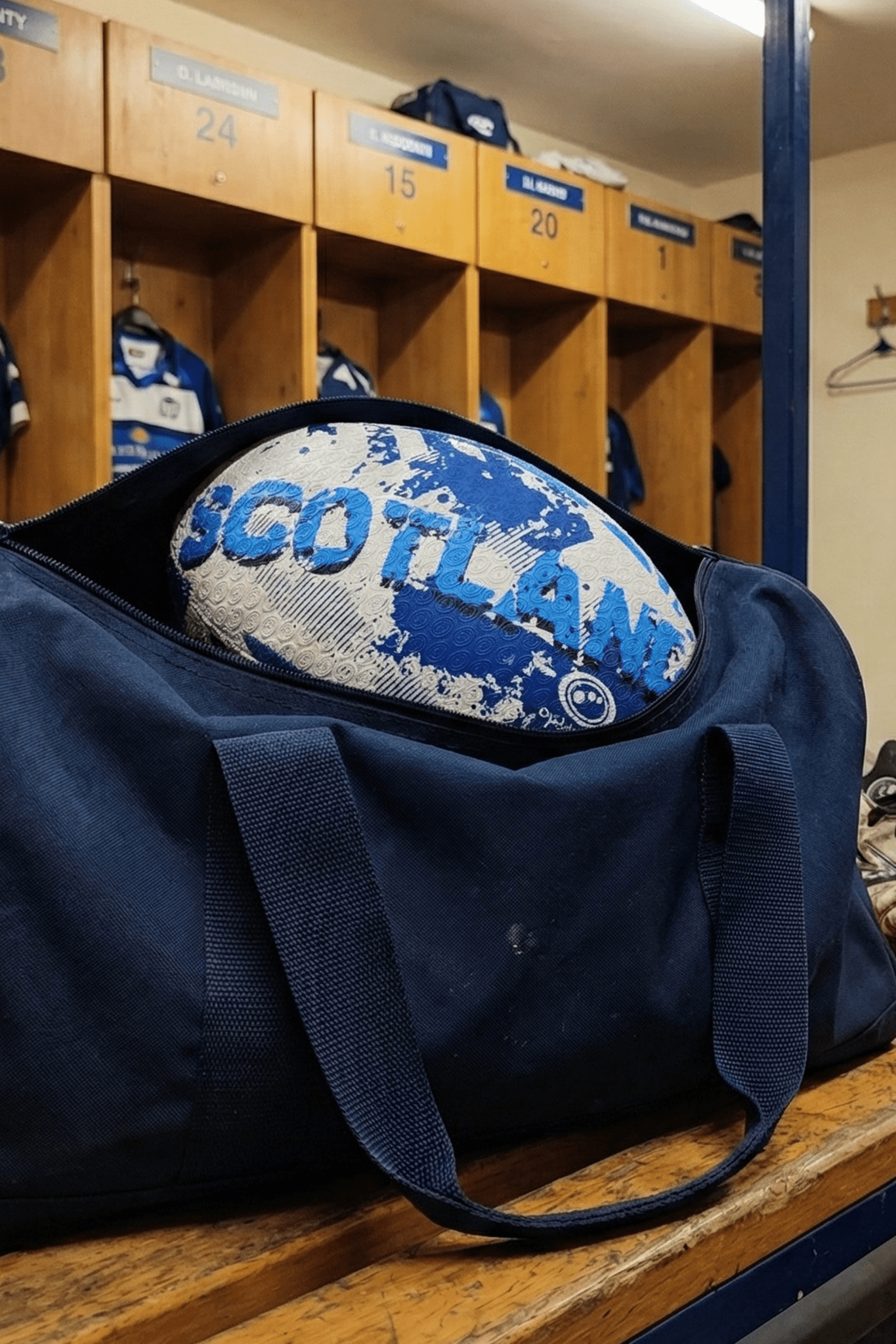 White and blue Optimum Scotland rugby ball in a navy kit bag on a changing-room bench - Optimum