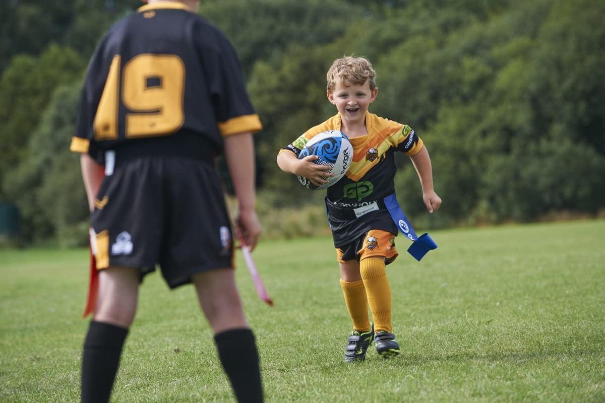 Young child in orange kit running with rugby ball wearing blue Optimum tag belt on a grass pitch