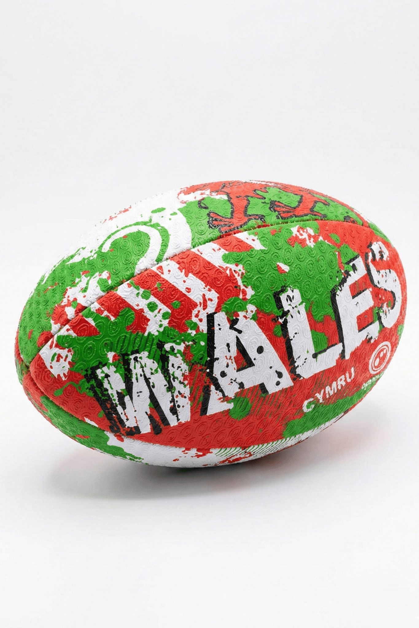 Green, red and white Optimum Wales rugby ball with WALES CYMRU print, resting on its side on white - Optimum