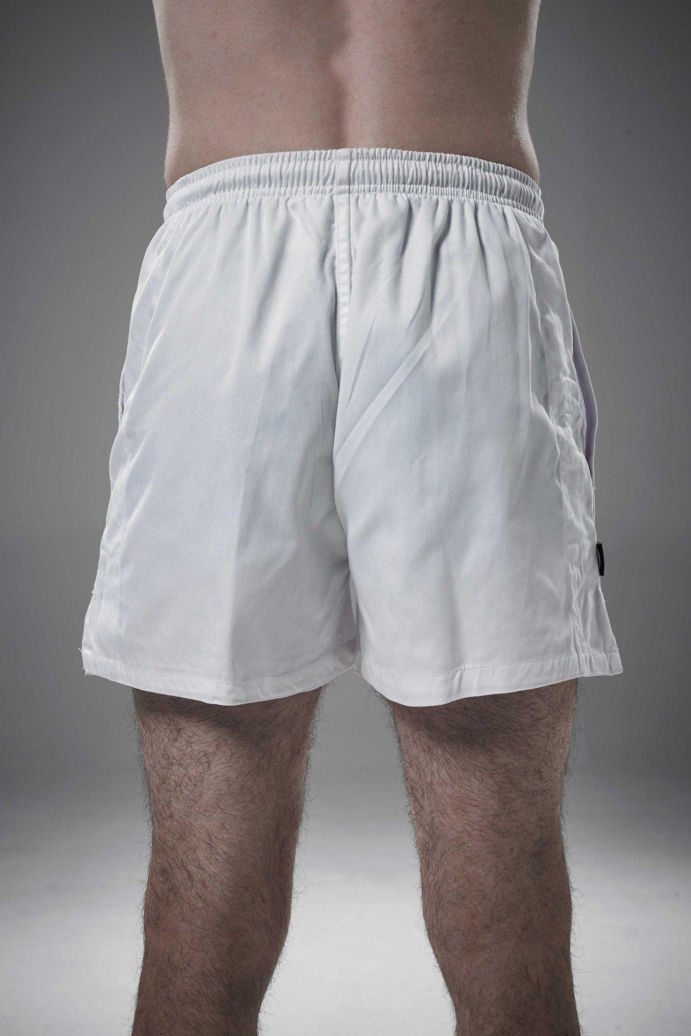 White Optimum rugby shorts worn by a man, rear view showing elasticated waistband, on grey studio background - Optimum