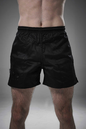 Man wearing black Optimum Auckland rugby shorts front-on with tonal logo on leg, grey background - Optimum