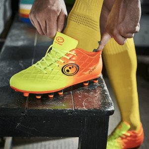 Player lacing neon yellow and orange Optimum football boot while wearing yellow knee socks, lifestyle - Optimum