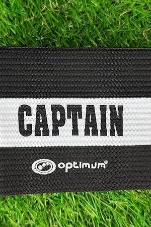 Black Optimum captain's armband with white CAPTAIN stripe and logo laid flat on grass - Optimum