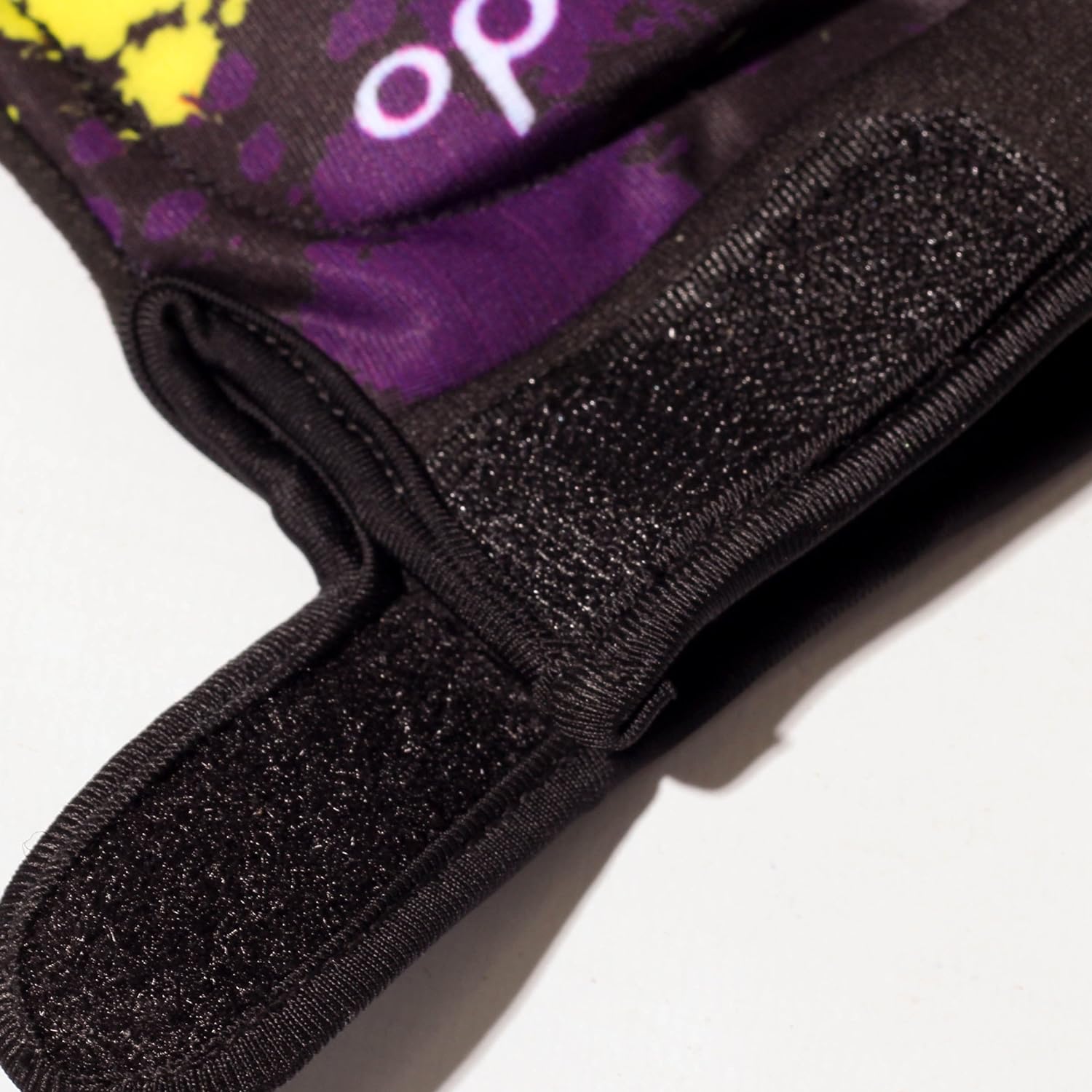 Close-up of black Optimum Fusion half-finger hockey glove Velcro cuff strap with purple splatter print - Optimum