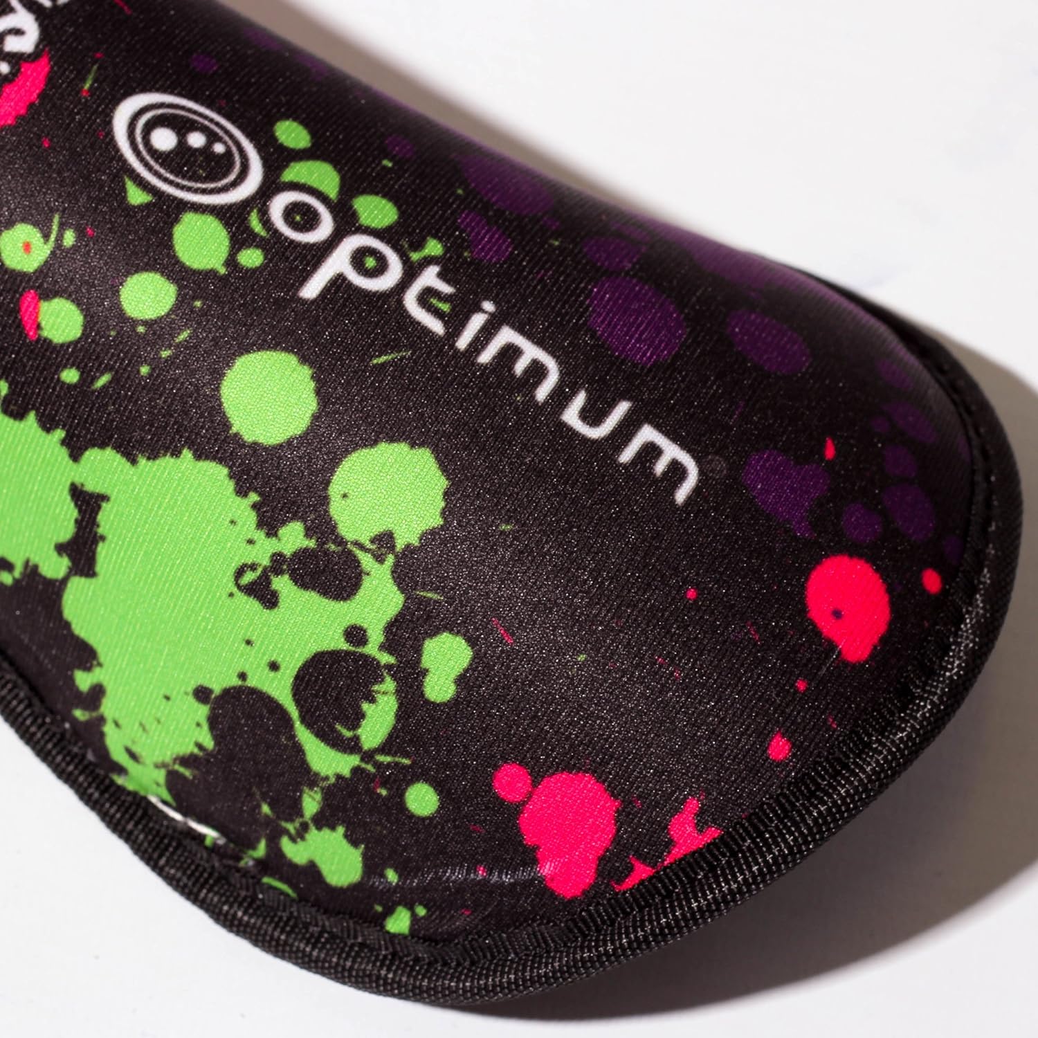 Close-up of black Optimum Fusion hockey shin guard with paint-splatter print and white logo, on white - Optimum