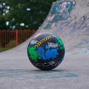 Black multicolour Optimum street football on tarmac at a graffiti skatepark - Optimum