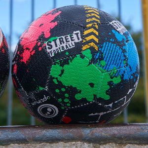Close-up of black multicolour Optimum street football resting on a metal rail outdoors - Optimum