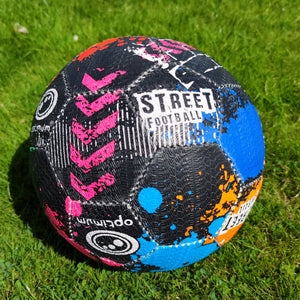 Black Optimum street football with pink, blue and orange splatter print, on grass - Optimum