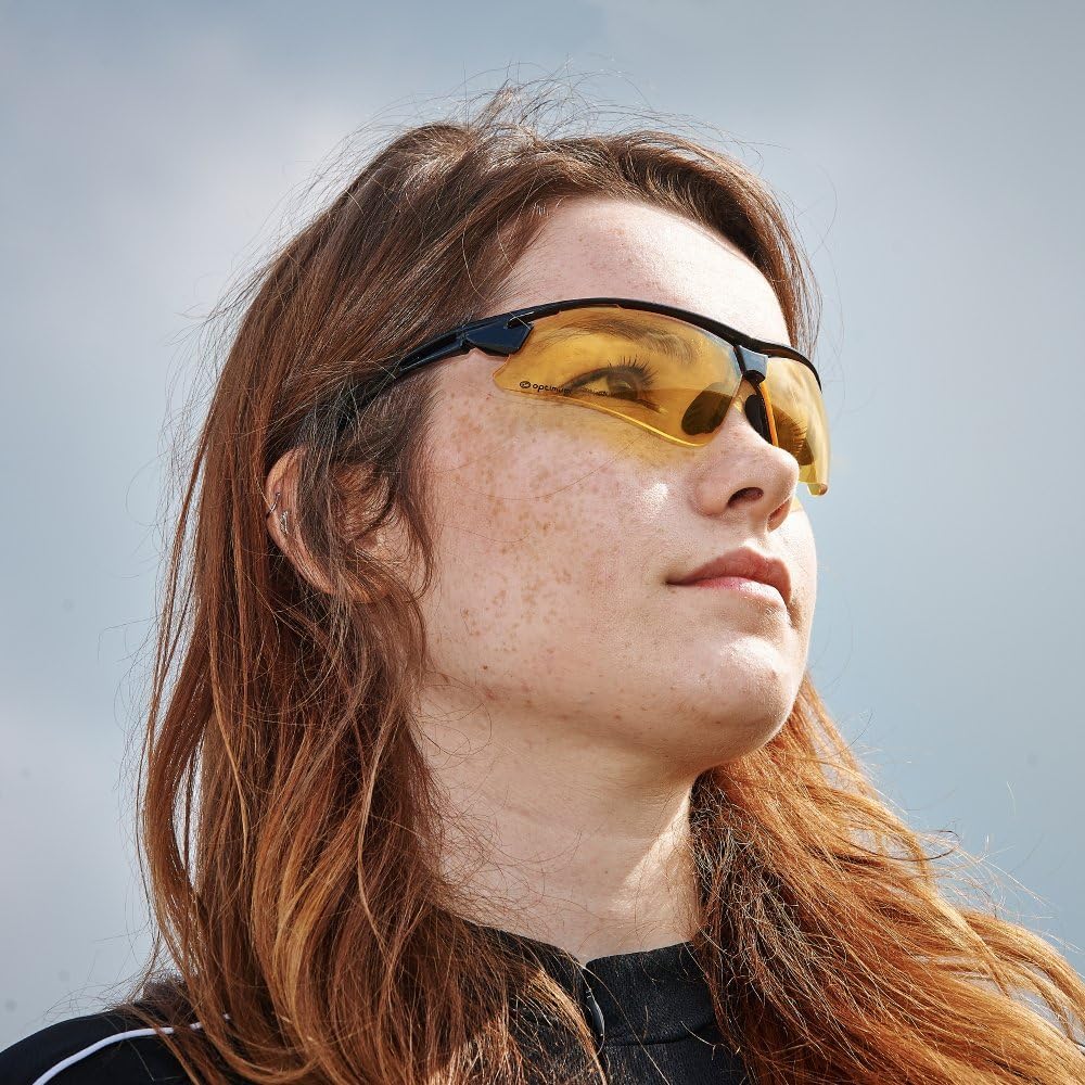 Woman wearing black Optimum sunglasses with amber lenses, looking up at cloudy sky, lifestyle shot - Optimum