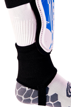 Blue and white Optimum Velocidade shin guard with black ankle sock and foot strap on lower leg, close-up on white - Optimum